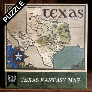 May include: A boxed 500-piece jigsaw puzzle featuring a fantasy map of Texas. The map is in shades of brown, green, and blue, with the word "Texas" at the top. The box has the words "Puzzle" and "Texas Fantasy Map" printed on it.