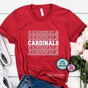 May include: Red t-shirt with the word "CARDINALS" repeated five times in white outlined text. The shirt is available in sizes XS-4XL and in various colors.