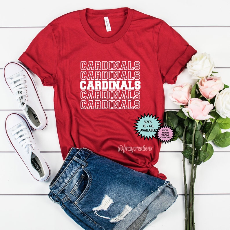 May include: Red t-shirt with the word "CARDINALS" repeated five times in white outlined text. The shirt is available in sizes XS-4XL and in various colors.