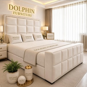 May include: A cream-coloured upholstered bed frame with a tufted headboard and footboard. The bedding includes pillows and a runner, each featuring the text DOLPHIN FURNITURE. A matching cream-coloured ceramic jar and a small round sphere sit in the foreground.