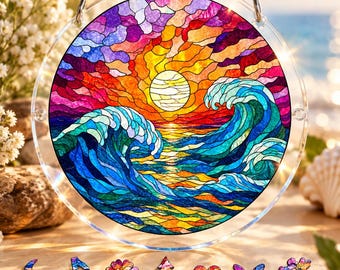Puede incluir: Un atrapasoles circular de vidrieras con un vibrante atardecer sobre olas oceánicas en tonos naranja, amarillo, morado y azul. Debajo de la pieza principal hay siete pequeñas formas decorativas que incluyen una luna, nota musical, flor, árbol, corazón y mariposa.