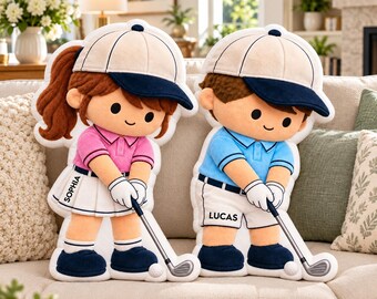 Puede incluir: Dos muñecos de peluche con temática de golf y gorras blancas y azul marino. El muñeco de la izquierda tiene pelo castaño, polo rosa y falda blanca con el nombre Sophia. El de la derecha lleva polo azul y pantalón corto blanco con el nombre Lucas.