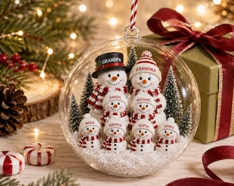 Puede incluir: Un adorno navideño esférico y transparente que contiene una familia de ocho figuras de muñecos de nieve en miniatura. Los muñecos llevan bufandas y gorros a rayas rojas y blancas, con los nombres impresos: Grandpa, Grandma, Daniel, Michael, Nora, Harper, Sofia y Emma.