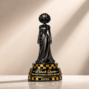 May include: A black figurine of a queen with an afro hairstyle wearing a gold crown and a flowing gown. The base is tiered with a black and gold checkered pattern, featuring the text "Black Queen THE MOST POWERFUL PIECE IN THE GAME" and "RAVEN".