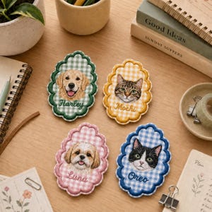 May include: Four scalloped-edge embroidered patches featuring portraits of pets on gingham backgrounds. The green patch shows a golden retriever named Harley, the yellow patch a tabby cat named Mochi, the pink patch a dog named Luna, and the blue patch a black and white cat named Oreo.