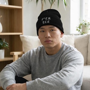 May include: Black beanie hat with the embroidered text "F*CK ICE" in white gothic lettering. The beanie is made of a soft material. A winter accessory.