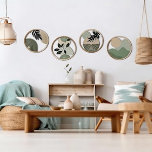Könnte beinhalten: Vier runde Wandkunstwerke mit abstrakten Designs in neutralen Tönen und grünen Akzenten. Jedes Stück ist in einem natürlichen Holzrahmen eingefasst. Die Kunst zeigt botanische und geometrische Formen und schafft eine moderne, minimalistische Ästhetik.