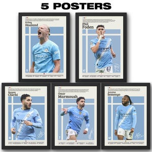 May include: Five framed posters featuring soccer players in light blue jerseys. Each poster has a player's name, number, and signature. The top text reads "5 POSTERS". The players are Erling Haaland, Phil Foden, Rayan Cherki, Omar Marmoush, and Antoine Semenyo.