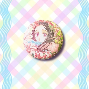 Puede incluir: Un bot&oacute;n redondo con una ilustraci&oacute;n de estilo anime de una ni&ntilde;a con pelo largo y oscuro y ojos rosas. El bot&oacute;n tiene un dise&ntilde;o floral y de mariposas con un fondo pastel.