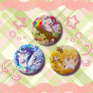 May include: Three round anime character button pins. The top pin has a holographic effect with multiple characters. The bottom left pin is blue with a character and stars. The bottom right pin is yellow with a character.