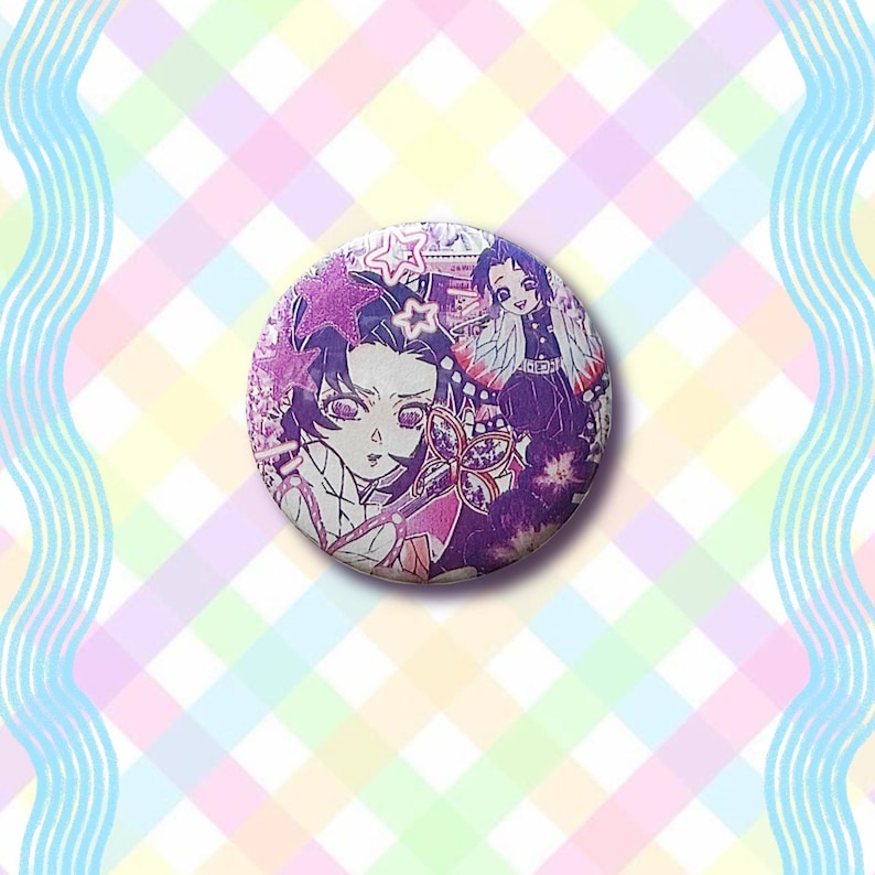 Puede incluir: Un bot&oacute;n redondo con una ilustraci&oacute;n de estilo anime en morado, rosa y blanco. El dise&ntilde;o presenta dos personajes y elementos decorativos. El fondo es un patr&oacute;n de cuadros pastel.