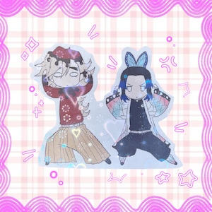 May include: Two anime-style character stickers. One character wears a red and brown outfit with tan pants. The other character wears a black outfit with a white and blue patterned coat and blue hair. The stickers are on a pink and white plaid background.