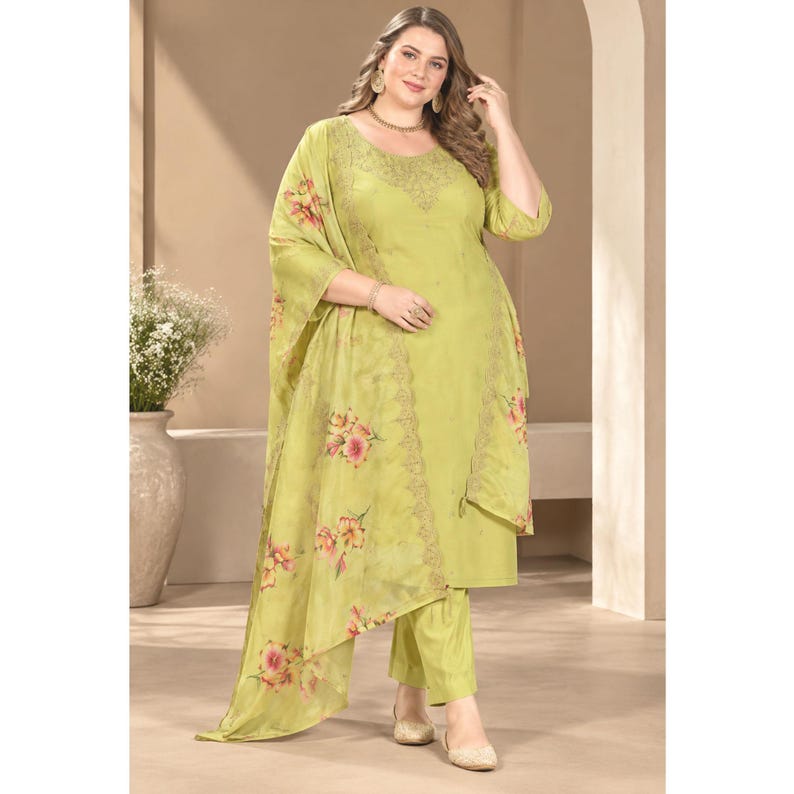 May include: A lime green three-piece outfit consisting of a long-sleeved tunic with a round neckline, matching straight-leg trousers, and a sheer, lightweight shawl draped over the shoulders, all featuring a delicate floral print in pink and orange.