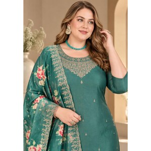 May include: A teal green long-sleeved tunic featuring a round neckline with intricate gold embroidery around the collar and scattered small gold motifs. A matching teal green shawl with a large floral print in pink and green drapes over one shoulder.