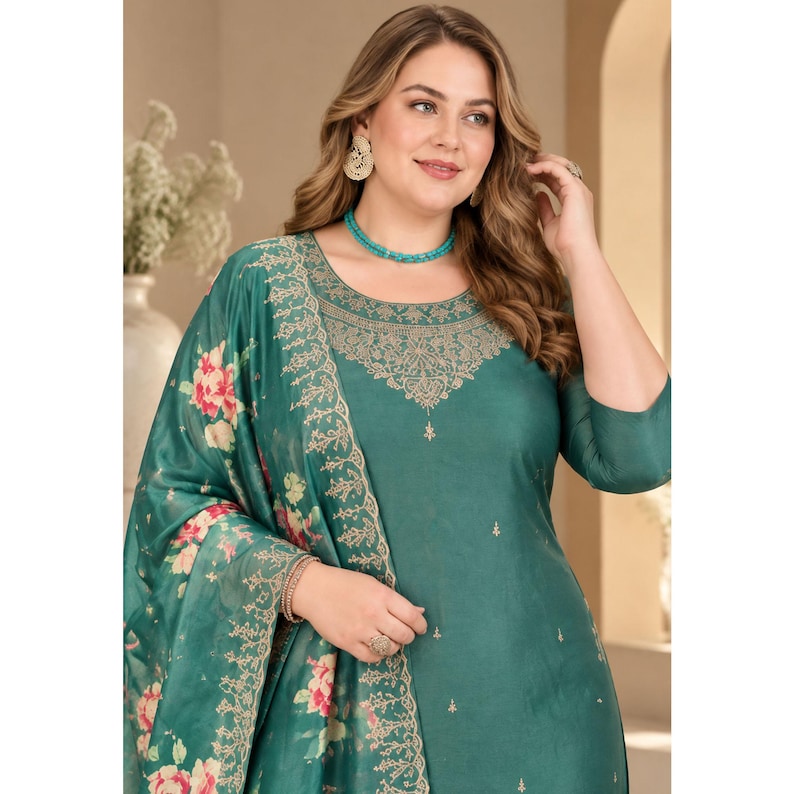 May include: A teal green long-sleeved tunic featuring a round neckline with intricate gold embroidery around the collar and scattered small gold motifs. A matching teal green shawl with a large floral print in pink and green drapes over one shoulder.