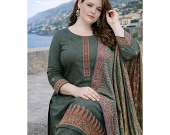 May include: A dark green salwar kameez set with intricate floral embroidery in red, orange, and gold. The set includes a long-sleeved tunic, matching pants, and a patterned shawl. The woman is wearing gold earrings.