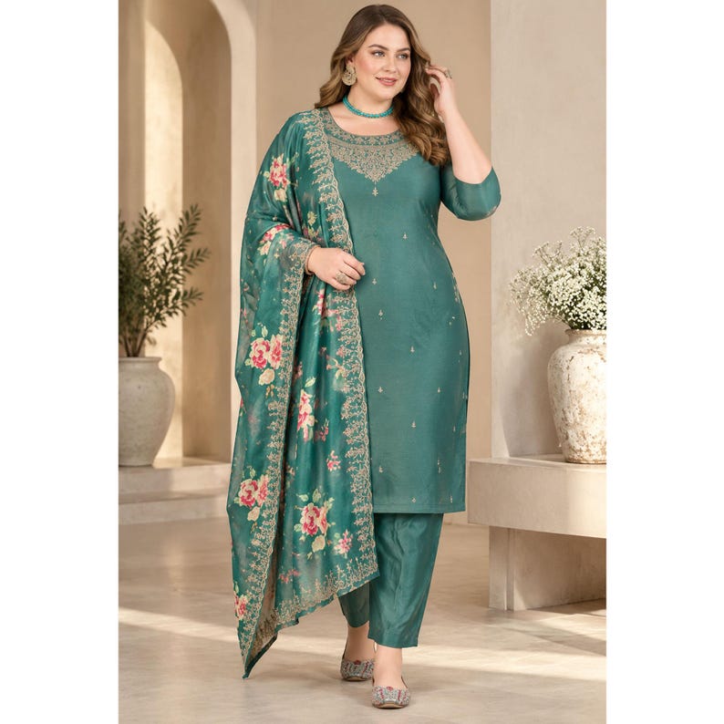 May include: A teal green three-piece ensemble consisting of a straight-cut tunic with a round neckline, matching trousers, and a coordinating dupatta. The tunic features intricate embroidery around the neckline, while the dupatta displays a floral print.