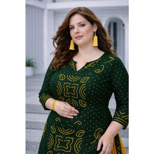 Könnte beinhalten: Eine Frau trägt ein dunkelgrünes Kleid mit gelben geometrischen Mustern und einem V-Ausschnitt. Das Kleid wird mit gelben Quastenohrringen und einem gelben Armband kombiniert. Das Outfit ist eine lebendige Kombination aus Farben und Mustern.