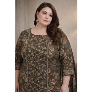 Puede incluir: Vestido verde oliva con estampado floral en rojo, azul y crema. El vestido tiene un escote cuadrado y mangas tres cuartos. Las mangas y el escote están ribeteados con un fino borde rojo. El vestido es de corte holgado.