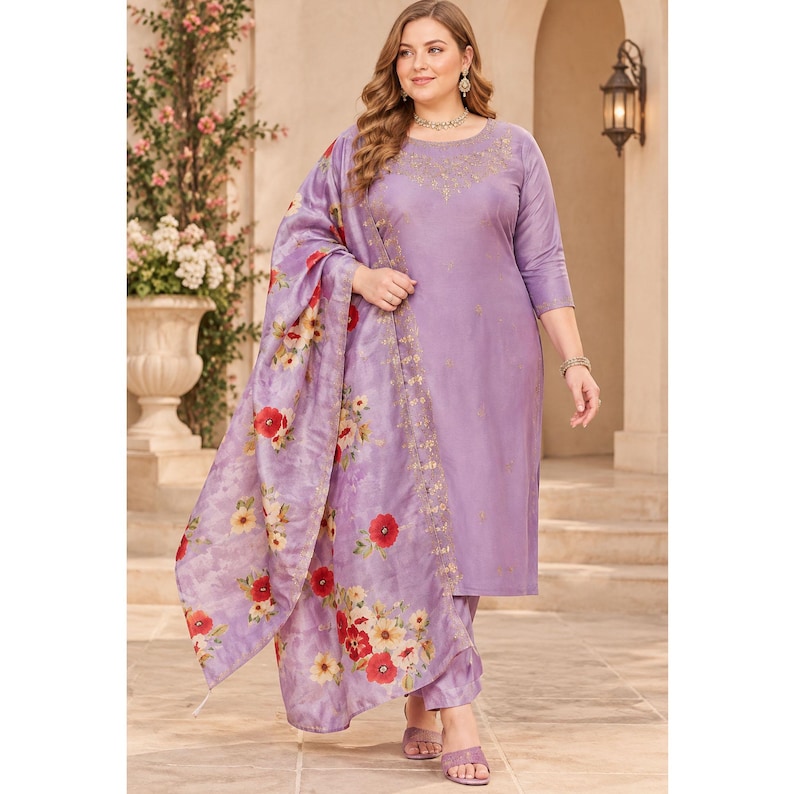 May include: A lavender-colored long-sleeved tunic and matching trousers set featuring delicate gold embroidery around the neckline. The outfit includes a coordinating lavender shawl adorned with a vibrant red and yellow floral print pattern.