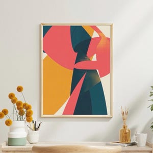 May include: Abstract art print in a wooden frame. The artwork features geometric shapes in coral, teal, yellow, and orange against a cream background. The print is displayed on a white wall, with a wooden desk and decorative items in the foreground.