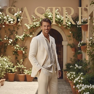 May include: A cream-colored suit with a double-breasted jacket, paired with matching pants and a patterned shirt. The model is wearing brown sandals. The background features a brick pathway, potted plants, and the word "SASTRE" in large letters.
