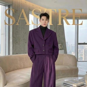 May include: A two-piece purple suit with wide-leg pants and a cropped blazer. The blazer has two front pockets and buttons. The model is wearing a black turtleneck. The word "SASTRE" is displayed in gold letters at the top of the image.