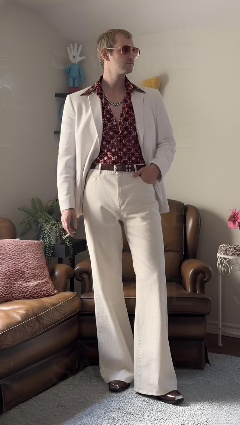 May include: A man in a white blazer, cream flared trousers, and a burgundy patterned shirt. He wears sunglasses and a gold chain. The outfit is reminiscent of 1970s fashion. The trousers are flared.