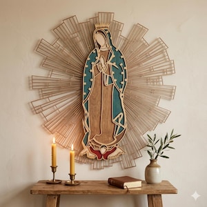Puede incluir: Un adorno de pared de madera que representa a la Virgen de Guadalupe, con una combinación de colores turquesa y marrón. La obra de arte está rodeada por un diseño de rayos de sol dorado. Dos velas encendidas y un jarrón con vegetación sobre una mesa de madera.