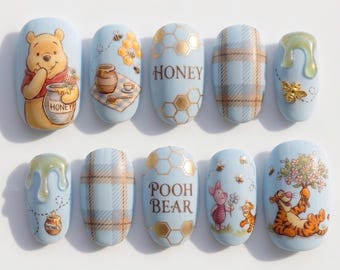 May include: Light blue nail art featuring Winnie the Pooh characters and honey-themed designs. Each nail showcases a different design, including Pooh Bear, Piglet, Tigger, honey pots, bees, and plaid patterns. The word "HONEY" and "POOH BEAR" are also featured.