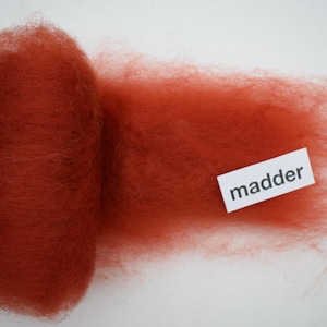 May include: A roll of red wool roving labeled "madder".