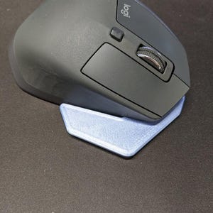 May include: A black Logitech wireless mouse with a silver scroll wheel and a blue mouse stand. The mouse has a logo on the top and is designed for ergonomic use.