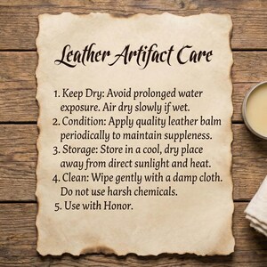 May include: Image of a parchment with "Leather Artifact Care" instructions, a tin of balm, and a folded cloth on a wooden surface. The instructions advise on drying, conditioning, storage, and cleaning leather items. The balm is in a silver tin, and the cloth is white.