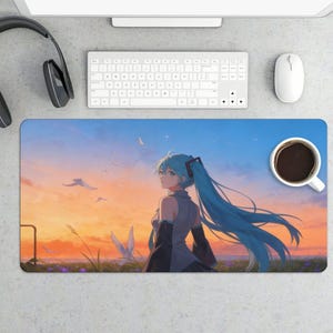 May include: A rectangular desk mat featuring an anime-style illustration of a woman with long, turquoise hair, set against a sunset sky with birds. A cup of coffee, a keyboard, a mouse, and headphones are also visible.