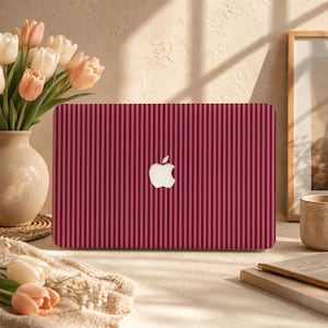 Könnte beinhalten: Eine Laptop-Hülle mit vertikalem Nadelstreifenmuster in abwechselnden Schattierungen von Dunkelrot und Kastanienbraun, zentriert mit einem weißen Apple-Logo. Die rechteckige Abdeckung ist für den Außendeckel eines tragbaren Computers konzipiert und zeigt ein durchgehendes lineares Design über die gesamte Oberfläche.