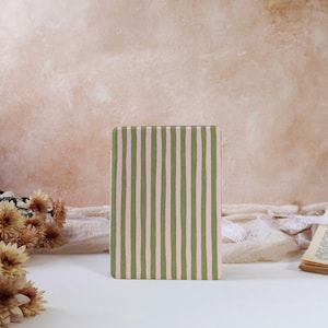 Puede incluir: Una funda rectangular para lector electrónico o tableta con un patrón de rayas verticales en tonos alternos de verde salvia y rosa pastel suave. Las rayas tienen un aspecto dibujado a mano, ligeramente irregular, en toda la superficie.