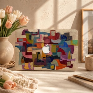May include: A laptop skin featuring a vibrant, abstract mosaic pattern of interlocking geometric shapes in shades of red, blue, green, yellow, and purple, centered around a white Apple logo on a textured, off-white, distressed background.