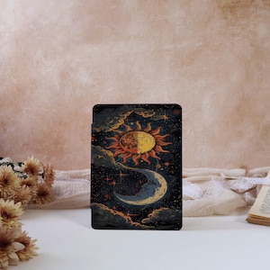 Puede incluir: Una impresión artística rectangular con un diseño celestial que presenta un sol y una luna sobre un cielo estrellado. El sol tiene rayos naranjas y está dividido en dos colores. La luna tiene forma de media luna y es de color azul claro. Nubes oscuras rodean el sol y la luna.