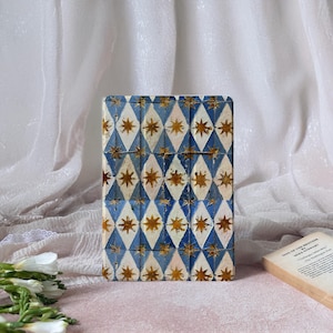 May include: A rectangular case with a repeating pattern of blue and white diamonds, each containing a gold star. The case is likely for a tablet or e-reader, offering both protection and a decorative touch.