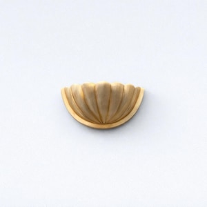 Könnte beinhalten: Ein dekoratives, halbkreisförmiges Holzakzentstück mit einem geriffelten, fächerartigen Design. Das Stück hat eine helle, natürliche Holzfarbe und ist vor einem weißen Hintergrund platziert. Dieser Artikel könnte als dekoratives Element in Möbeln oder der Innenarchitektur verwendet werden.