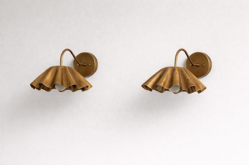 Pair of vintage brass wall sconces with downward, ruffled shades and curved arms, antique brass finish.