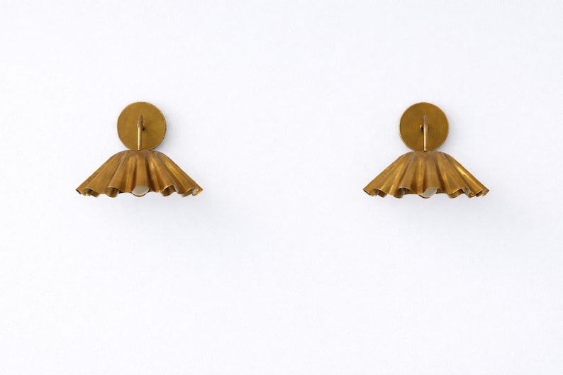 Pair of vintage brass wall sconces with downward, ruffled shades and curved arms, antique brass finish.