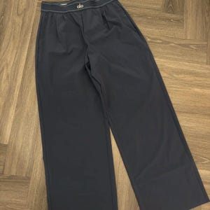 Puede incluir: Pantalones anchos de color azul marino oscuro con cintura blanca y la marca "alo" en blanco. Los pantalones tienen un corte relajado y est&aacute;n hechos de una tela lisa y mate. Los pantalones est&aacute;n doblados cuidadosamente.