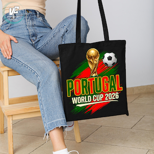 Może przedstawiać: Czarna torba typu tote z nadrukiem graficznym przedstawiającym złote trofeum Pucharu Świata oraz czarno-białą piłkę nożną. Projekt zawiera napis PORTUGAL oraz WORLD CUP 2026 pogrubioną czcionką na tle z czerwonymi i zielonymi wzorami pociągnięć pędzla.