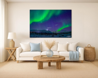 May include: A canvas print depicting the aurora borealis, with vivid green and purple lights against a dark blue sky. The scene includes snow-covered mountains and a bright moon. The artwork measures 102x152cm.