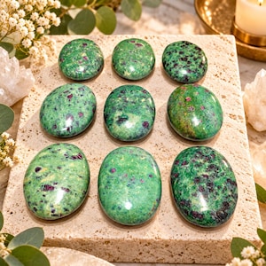 May include: Nine polished oval stones arranged in a three-by-three grid. Each stone features a vibrant green base colour with distinct dark green and magenta-coloured inclusions throughout the smooth, glossy surface of the mineral specimens.