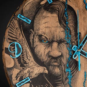 May include: Wooden wall clock featuring a detailed engraving of a stern-faced man with an eagle. The clock face is brown with blue accents for the numbers and hands. The man has a long beard and an intense gaze.