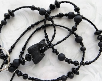 May include: Black beaded lanyard with a black silhouette of a Scottish Terrier charm and a silver swivel clip.