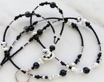 May include: Black and white beaded lanyard with a white heart charm featuring a black and white design. The lanyard has a silver key ring.