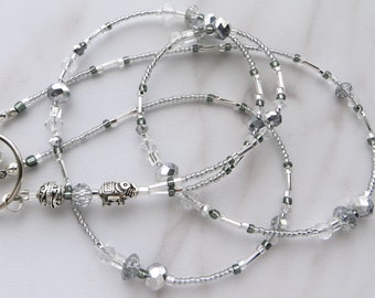 May include: A silver beaded lanyard with a silver elephant charm and a silver key ring. The lanyard is made of small silver beads and clear crystal beads.